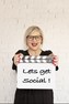 Social Media Business Woman holding Film Clap Board with type on board saying "Lets Get Social"